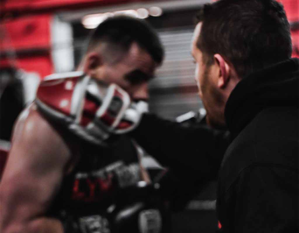 Boxer training with coach using focus pads