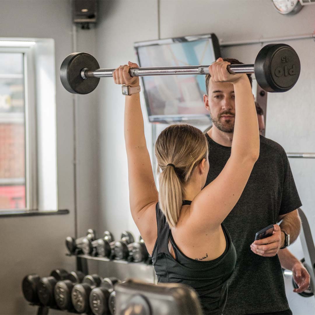 Coach guiding member through overhead press
