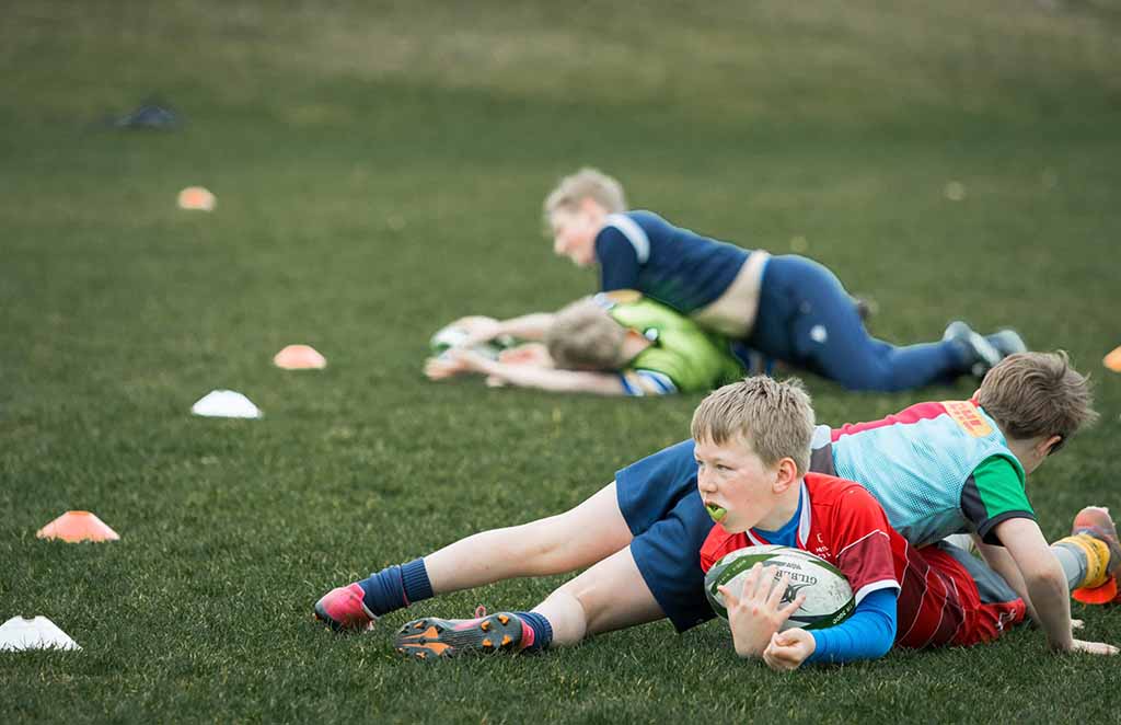 Young rugby players practising tackling during training session