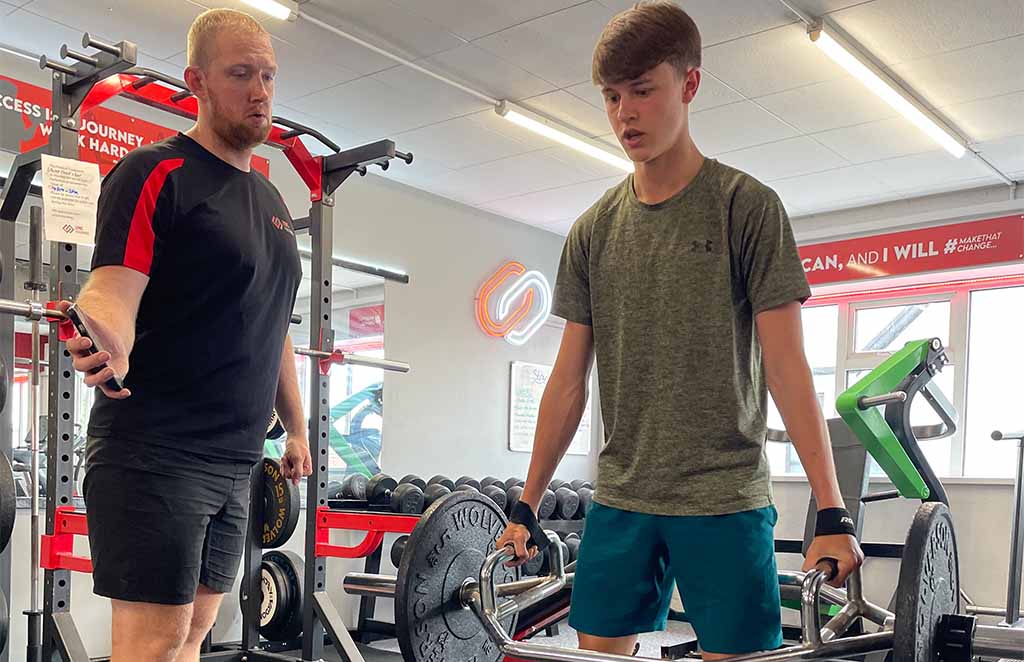 Coach guiding athlete through strength exercise at Lync Active