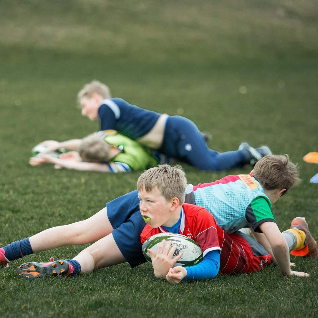 Children practising rugby drills on grass field