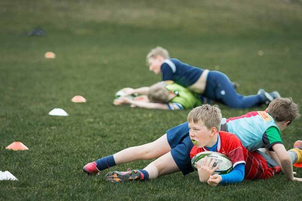 Young rugby players practising tackling during training session