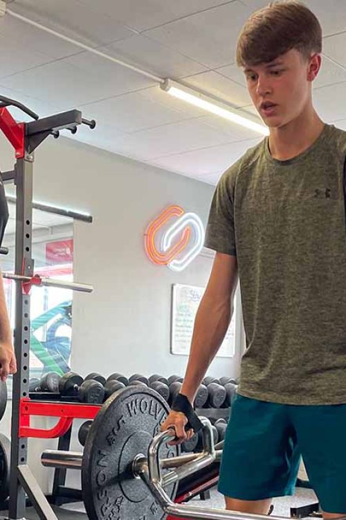 Coach guiding athlete through strength exercise at Lync Active